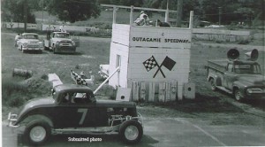 George Giesen receives the checkered flag for a victory at Outagamie Speedway in his No. 7 Plymouth coupe in the early 1960s. Note the upright railroad ties that formed the walls erected around the track at this time. (Submitted photo)